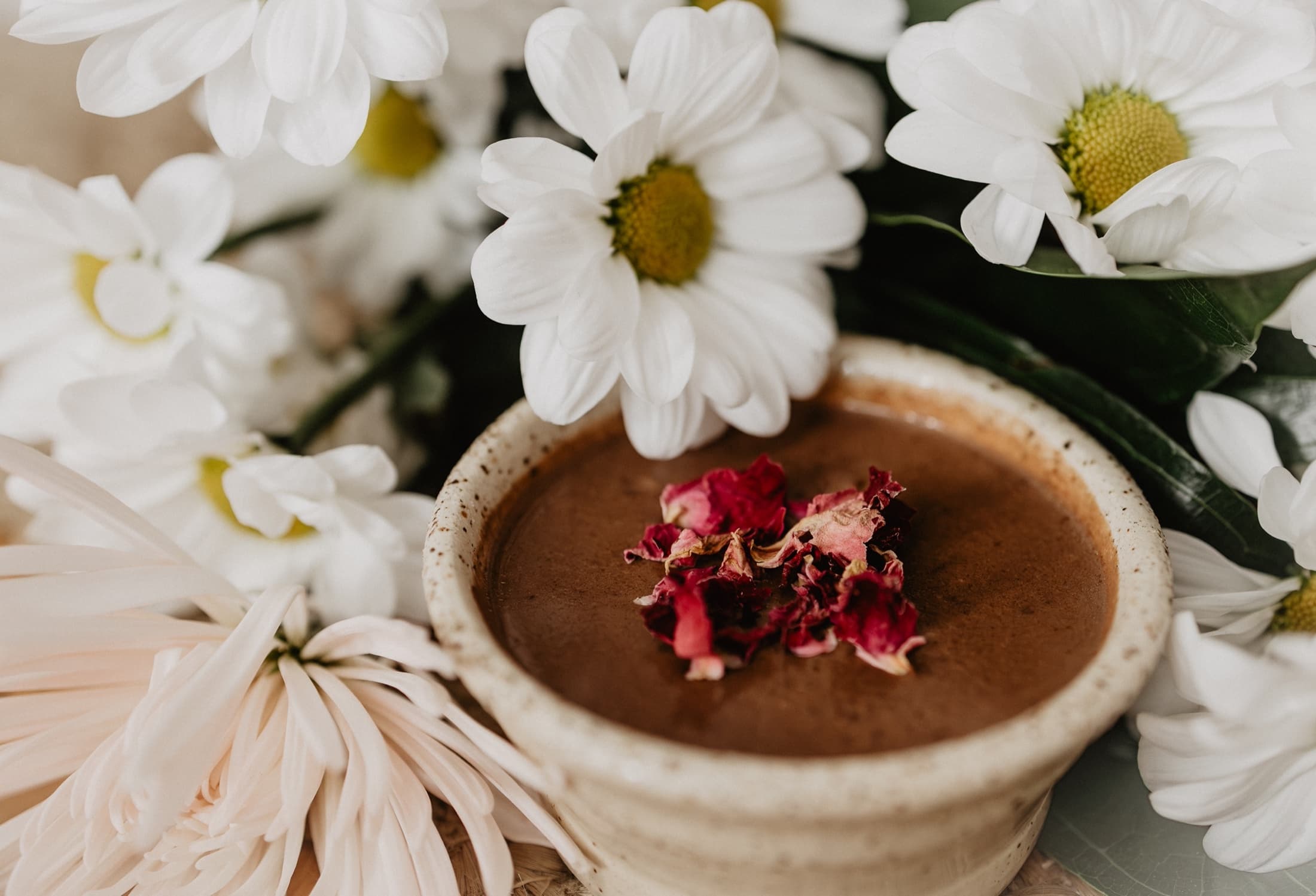 Warmer Kakao mit weißen Blüten und Rosenblättern